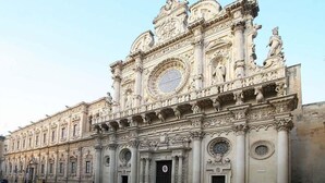 A grand historical building with intricate carvings and statues, featuring a large central dome and multiple arched windows. - IL RIFUGIO DEI TEMPLARI (Lecce)