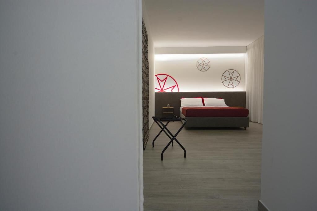 Ein modernes Schlafzimmer mit einem Bett, einem kleinen Tisch und abstrakter Wandkunst.