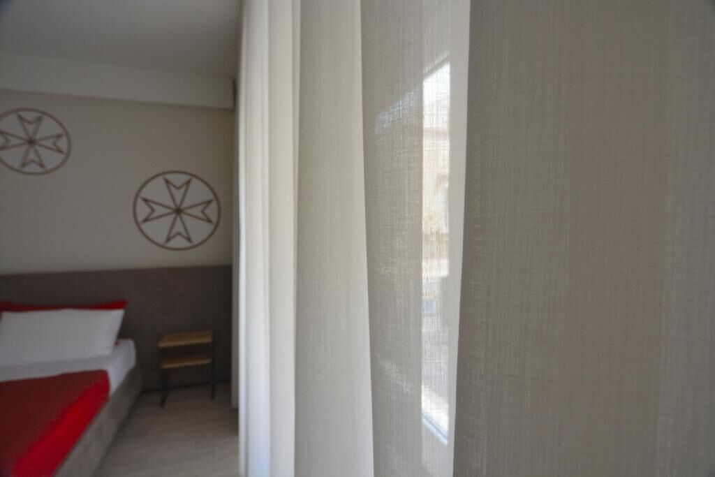 A bedroom with a bed, a small table, and two wall decorations.