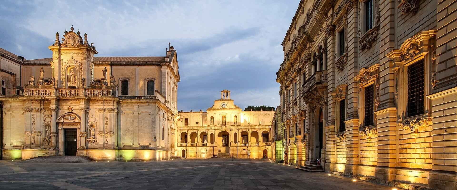 A historic plaza with ornate buildings, including a church with a bell tower and a large dome.