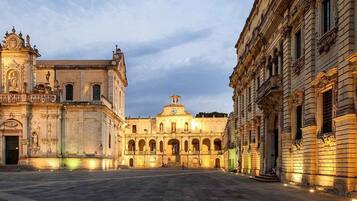 A historic plaza with ornate buildings, including a church with a bell tower and a large dome.