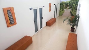 A corridor with benches, doors, and a painting of the Leaning Tower of Pisa. - Hotel Aston Cúcuta (San José de Cúcuta)