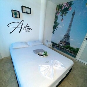 Ein Hotelzimmer mit einem Bett, einem Nachttisch und einer Wand mit einem Bild vom Eiffelturm.