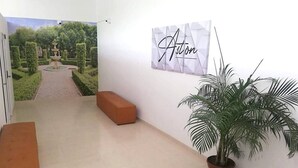 A hallway with a bench, a potted plant, and a wall-mounted sign that reads "Aston." - Hotel Aston Cúcuta (San José de Cúcuta)