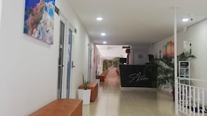 A hotel reception area with a reception desk, a bench, and a corridor leading to other rooms. - Hotel Aston Cúcuta (San José de Cúcuta)