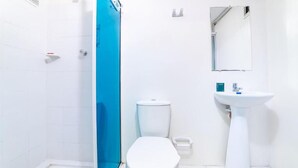 A bathroom with a white toilet, a sink, and a shower area. - Hotel Aston Cúcuta (San José de Cúcuta)