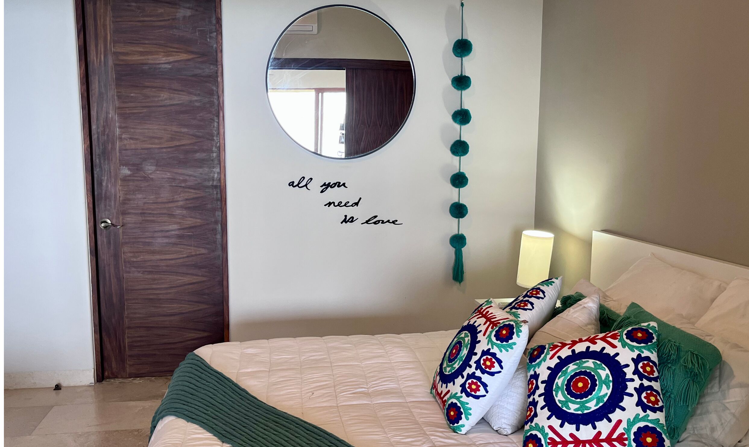 A bedroom with a bed, a mirror, and a wall with a motivational quote.