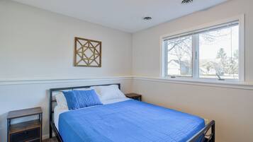 A bedroom with a bed, a nightstand, a window, and a decorative wall piece.
