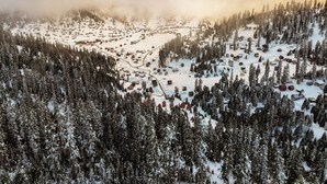 An aerial view of a snow-covered village with houses scattered among dense forests. - Ire Palace (Khulo)