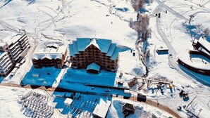 An aerial view of a lodge with a central building surrounded by snow-covered terrain and a small lake. - Ire Palace (Khulo)