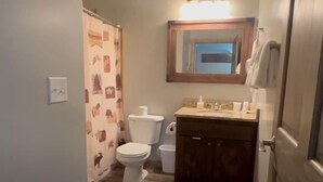A small bathroom with a toilet, sink, and shower curtain. - King Room at Ponds Lodge Cabin 6 Unit 3 (Island Park)