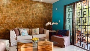 Un salon avec un mur en pierre, un canapé, une table basse et une vue à travers une porte vitrée.