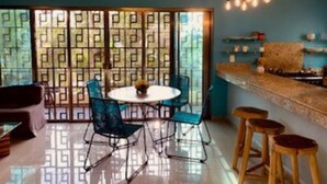 Un espace repas avec une table ronde, des chaises bleues et un comptoir de bar avec des tabourets.