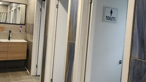 A restroom with multiple doors, a tiled floor, and a sign indicating the presence of toilets.