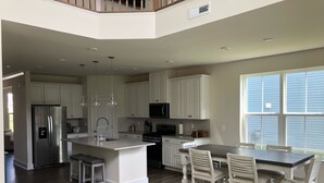 A spacious kitchen with white cabinets, a stainless steel refrigerator, and a large island with bar stools. - NEW - Spacious 4-bedroom near Bethany Beach in Bishops Landing resort + shuttle (Millville)
