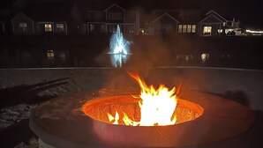 A fire pit with flames, surrounded by a stone structure, and houses in the background. - NEW - Spacious 4-bedroom near Bethany Beach in Bishops Landing resort + shuttle (Millville)