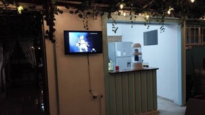 Une pièce avec un téléviseur fixé au mur, un petit comptoir avec une machine à café et une porte donnant sur une autre pièce.