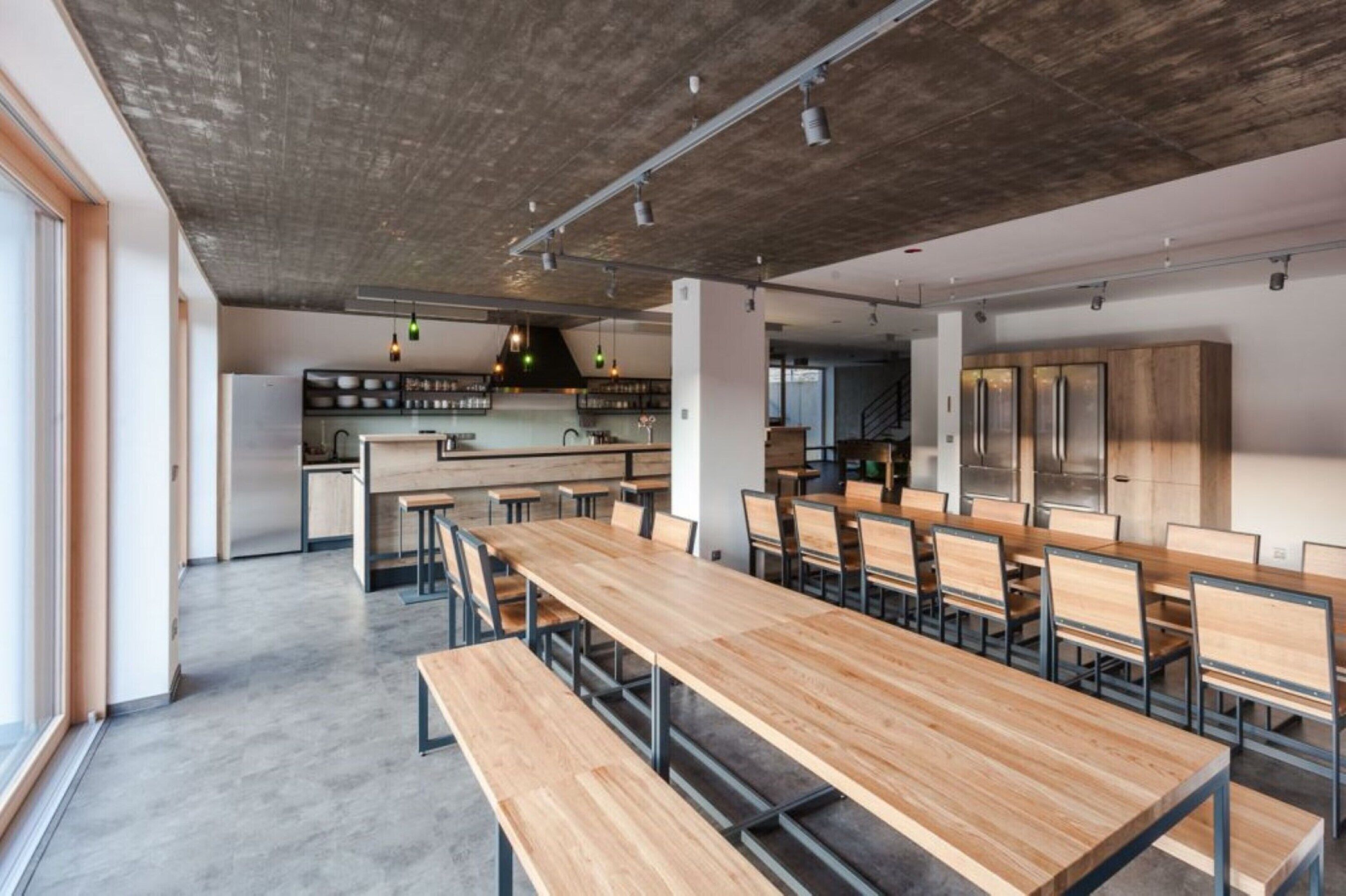 A modern kitchen with wooden cabinets, a central island, and a dining area with wooden tables and chairs.