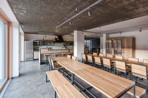 A modern kitchen with wooden cabinets, a central island, and a dining area with wooden tables and chairs.