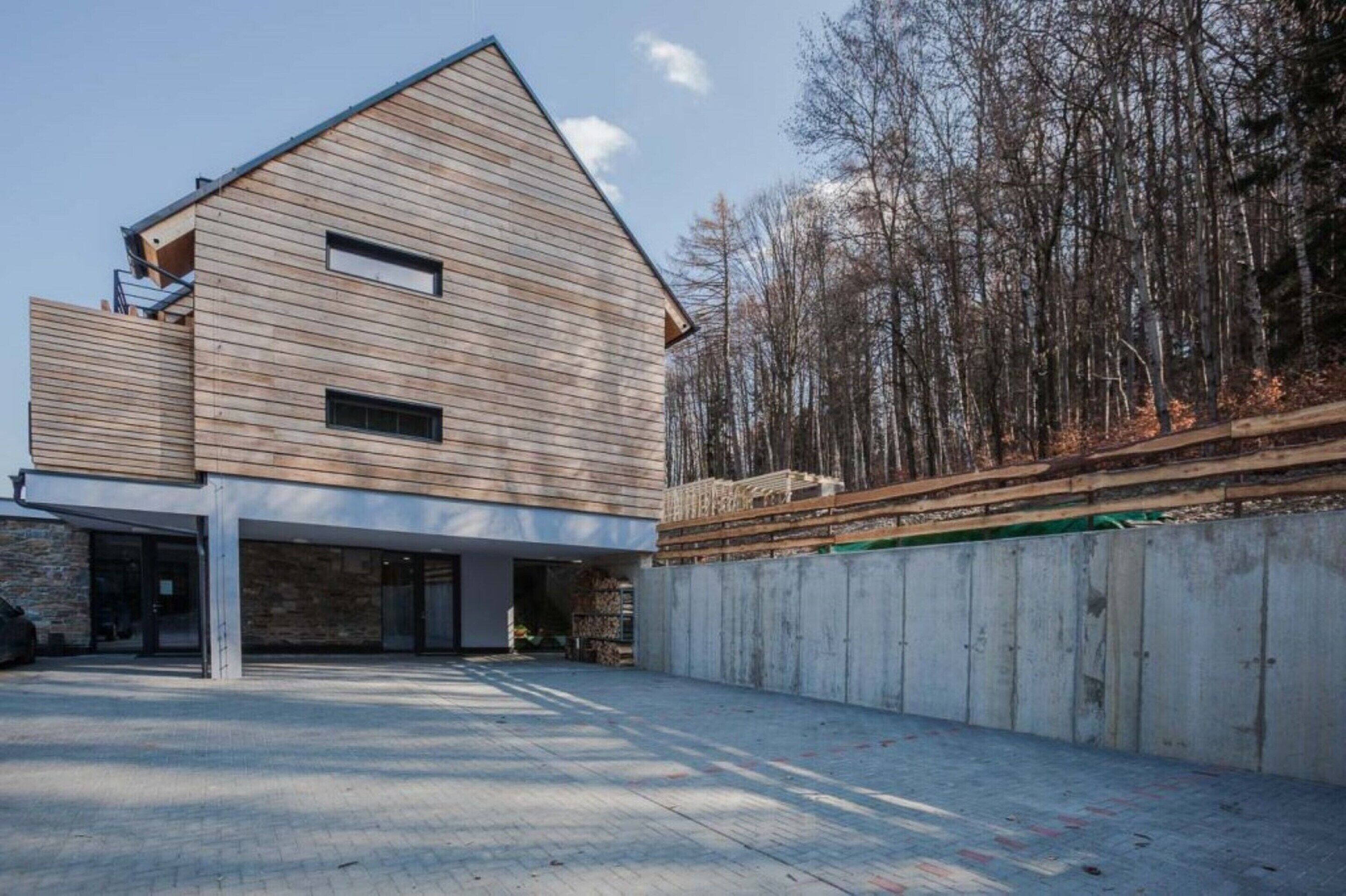 A modern two-story house with a sloped roof, large windows, and a garage.