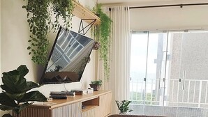 Een moderne woonkamer met een flatscreen-tv, een houten salontafel, een leren fauteuil en een balkon met uitzicht.