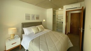 Un dormitorio con cama, mesita de noche, lámpara y un vestidor con estantes.