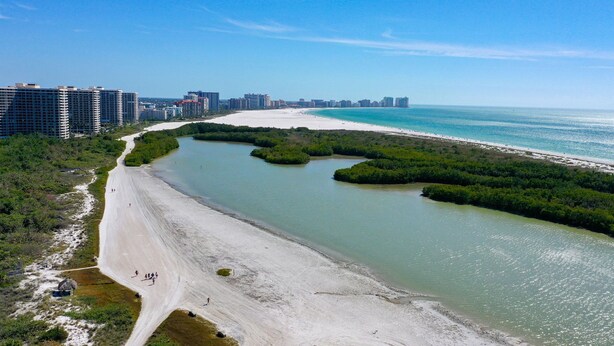 Une zone côtière avec une plage de sable, une rivière et, au loin, une vue sur la ville.
