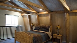 A wooden-framed bedroom with a bed, two bedside tables with lamps, and a window. - Blue Cabin in Idaho Springs (Idaho Springs)
