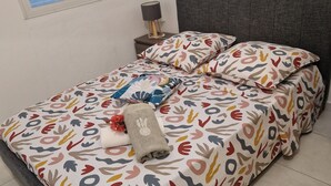 Un lit bien fait, avec une literie à motifs, une lampe de chevet et une fenêtre équipée de stores.