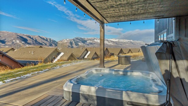 Una vasca idromassaggio su un pontile di legno con vista sulle montagne.