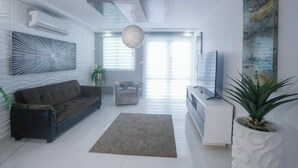 A modern living room with a sofa, a coffee table, a TV, and a potted plant. - Distribución (mayaguez)