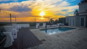 A rooftop pool area with white lounge chairs and a wooden deck. - Distribución (mayaguez)
