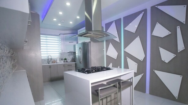 A modern kitchen with a central island, stainless steel appliances, and a contemporary design. - Distribución (mayaguez)