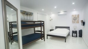 A bedroom with bunk beds, a single bed, a bedside table, a lamp, and wall decorations. - Distribución (mayaguez)