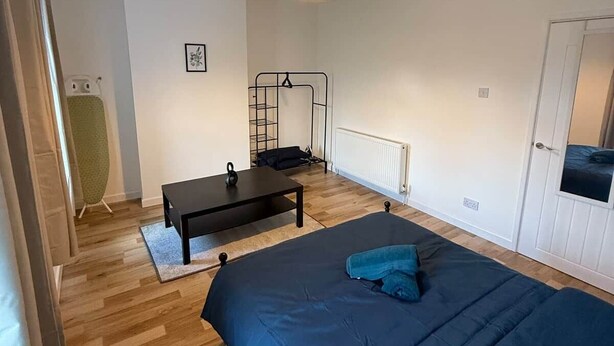 Een slaapkamer met een bed, een bureau, een ladder en een radiator.