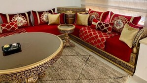 Ein Wohnzimmer mit einem roten Sofa, goldenen Akzenten und einem runden Couchtisch.