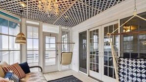 Une véranda avec un sol à motifs, un fauteuil suspendu et un hamac.
