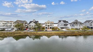 Une rangée de maisons au bord d’un lac paisible, sous un ciel dégagé.