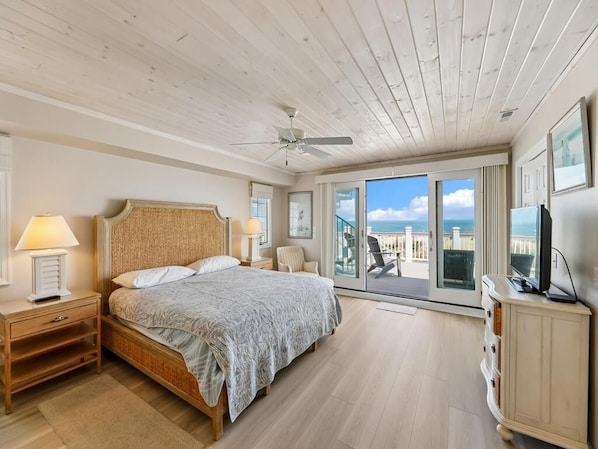 Une chambre à coucher avec un lit, des tables de chevet, une télévision et un balcon avec vue.
