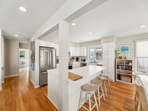 Una cocina moderna con una isla central, electrodomésticos de acero inoxidable y vistas al área de estar.
