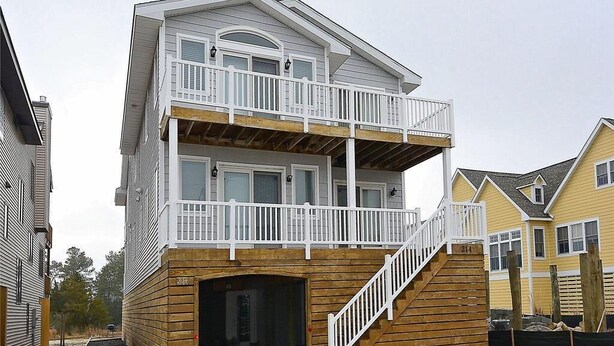 Un bâtiment à deux étages doté d’une terrasse en bois et d’un balcon.