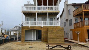 Un bâtiment à deux étages doté d’un balcon à l’étage supérieur, d’un garage au rez-de-chaussée et d’une terrasse en bois.