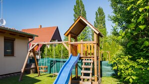 Eine hölzerne Spielkonstruktion mit Rutsche und Kletterleiter in einem Garten.