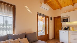 Ein gemütliches Wohnzimmer mit einer Couch und einer Küchenzeile, die einen Kühlschrank, eine Mikrowelle und eine Kaffeemaschine umfasst.