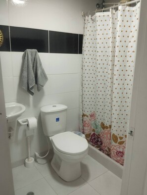 Baño con inodoro, lavamanos y cortina de ducha.