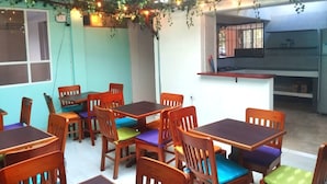 Un espace repas avec des tables et des chaises en bois, dont certaines sont agrémentées de coussins colorés.