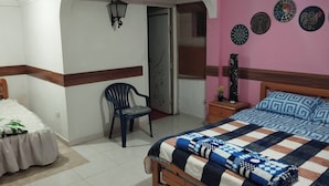 Une chambre à coucher avec un lit, une chaise, une table de chevet et des assiettes décoratives accrochées au mur.