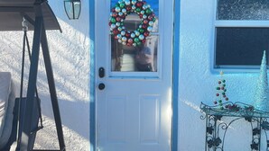 A front door with a Christmas wreath, a small Christmas tree, and a swing set.