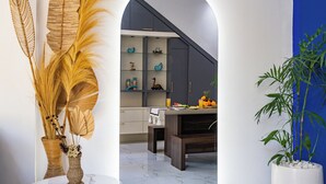 A modern kitchen with a dark countertop, white cabinets, and a blue accent wall. - Villa Ashëla (By JB Villas) (Bali)