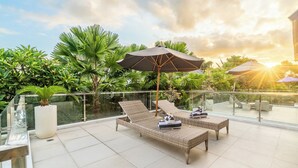 A rooftop terrace with two wicker lounge chairs, a large umbrella, and a potted plant. - Villa Ashëla (By JB Villas) (Bali)